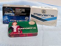 Front view of two tins showing Player's Light and Macdonald Export 'A' graphics
