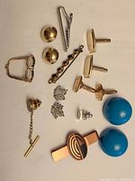 All items laid out including cufflinks, brooches, tie clips, earrings