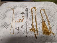 Overall view of four necklaces and loose pendants/charms laid out on lace cloth