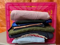 All eight folded fabric pieces stacked in pink crate