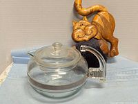 Full view of glass teapot with lid and cat pincushion