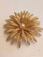 Front view showing gold-tone flower design and faux pearl center
