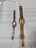 Two wristwatches laid flat for size and style comparison