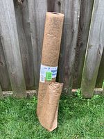 Full roll standing against fence showing overall condition and torn wrap
