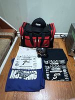 Overall lot showing duffel bag, cap, three shirts, sunglasses