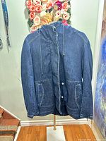 Front view of blue denim sherpa-lined hooded jacket on hanger