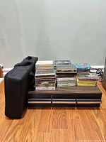 Cassette tapes stacked on wood drawer unit with carrying case beside