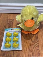 Plush duck beside packaged rubber duck candles