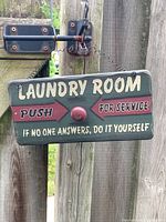 Front of green wooden laundry room sign showing text and faux button