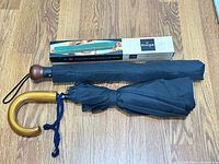Two closed Knirps umbrellas, sleeve, and branded box on wood floor