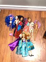 Group shot of nine dolls arranged on wooden floor