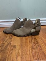 Side view showing overall profile, color, heel height, perforated faux-suede upper and buckle detail.
