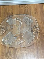 Full view of clear glass platter showing embossed cheese names and grapevine design
