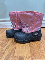 side view of both boots showing pink glitter upper and black rubber lower