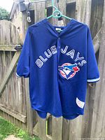 Front view of Blue Jays jersey hanging on hanger showing team name and logo