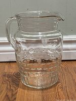 Full view of clear and frosted glass pitcher showing shape, handle and etched grape motif