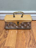 Front view of woven metal vanity case showing vinyl top, latch, and handle