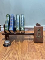 Overall lot showing wooden rack holding four books and desk bell