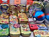 overall lot showing tins, sealed deck, Great Ball, keychain game, coins and figure
