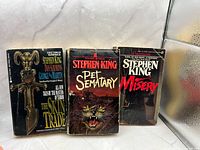 Front covers of three paperback titles Pet Sematary, Misery, The Skin Trade