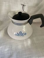 Front view showing blue cornflower design, handle, lid