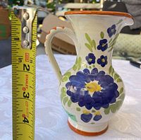 Side view showing height and floral motif with blue flower and tape measure indicating ~5 inches