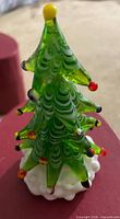 Front view of green glass Christmas tree figurine with ornaments on white base