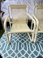 Front view of two off-white tubular sling chairs on patterned rug
