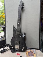 Full view of Power Gig guitar controller standing upright with strap and PS3 game case