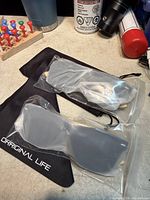 Two sealed pairs of sunglasses with pouches visible