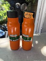 Two orange U-Haul metal water bottles standing upright