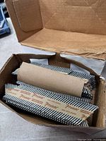 Open cardboard box showing several paper-collated strips of Paslode galvanized nails