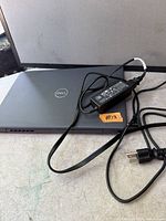 Closed Dell laptop lid with Dell logo and AC adapter