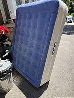 Full view of air mattress standing on side showing blue top and white sides