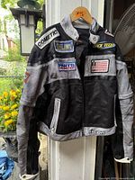 Front view of Icon motorcycle jacket hanging, showing patches, colours, overall condition