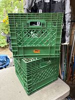 Two stacked plastic milk crates, green upper and green lower