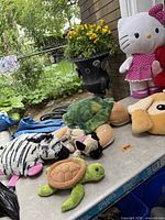 Group of assorted plush toys on table including zebra, turtle, pug, small turtle and tan dog