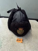 Front view of black faux fur O.P.P. winter hat with crest badge