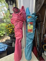 Two folded camping chairs in pink and teal carry bags
