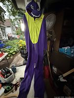 Front view of purple and yellow dragon kigurumi hanging full length