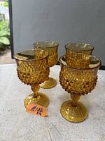Four amber diamond point pattern goblets standing on table