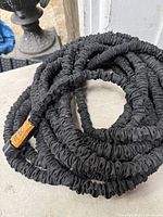 Black expandable hose coiled on surface
