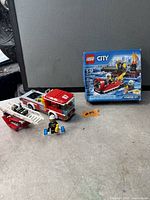 Boxed LEGO City 60106 set alongside loose fire truck build