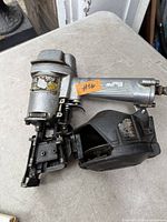 Left side view of Hitachi pneumatic coil nailer showing magazine and overall wear