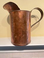 Side view of copper pitcher showing handle, body and spout