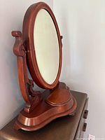 Front view showing oval mirror, ornate supports, shaped base