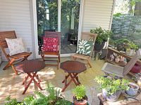 Patio setup showing four wooden folding chairs, two folding side tables, three decorative cushions
