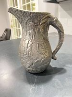 Left side view of elephant pitcher showing figural relief and patina