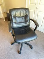 front view of black office chair showing seat, backrest, armrests, casters