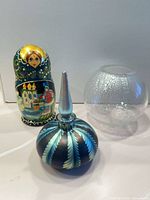 Matryoshka doll, iridescent perfume bottle with detached stopper, crackle glass votive overall view